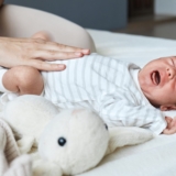Unrecognizable,Woman,Massaging,Tummy,Of,Her,Crying,Sick,Son,Trying