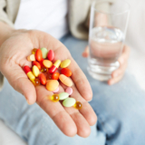 Pills, tablets, vitamins and drugs heap in mature hands, closeup view.
