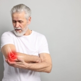 Arthritis.,Senior,Man,Suffering,From,Pain,In,Elbow,On,Grey