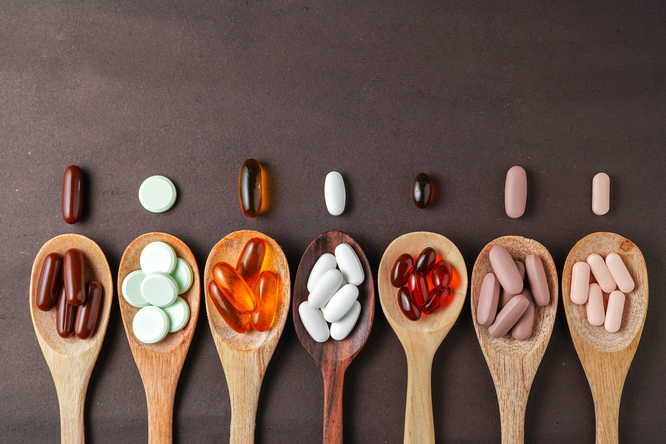 Assorted,Different,Pills,,Supplement,Vitamin,,In,A,Wooden,Spoon,On
