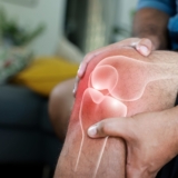 Close-up,Of,Hand,Holding,Painful,Injured,Knee,With,Red,Inflamed